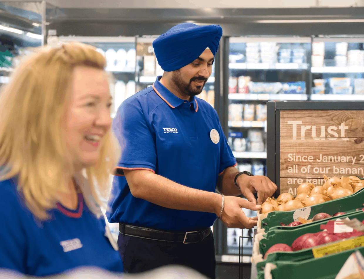 2 Tesco employees putting out veg